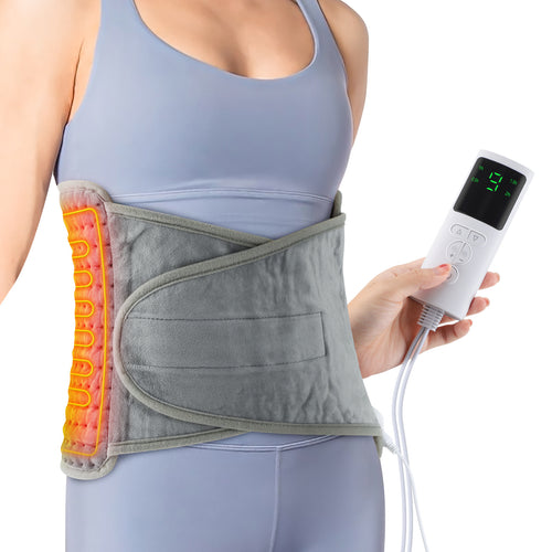 Femme portant le coussin chauffant Cocon autour de la taille, télécommande en main