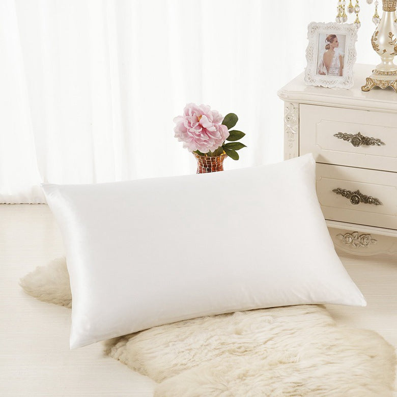 Taie d'oreiller Nacre en satin blanc sur un oreiller dans une chambre lumineuse